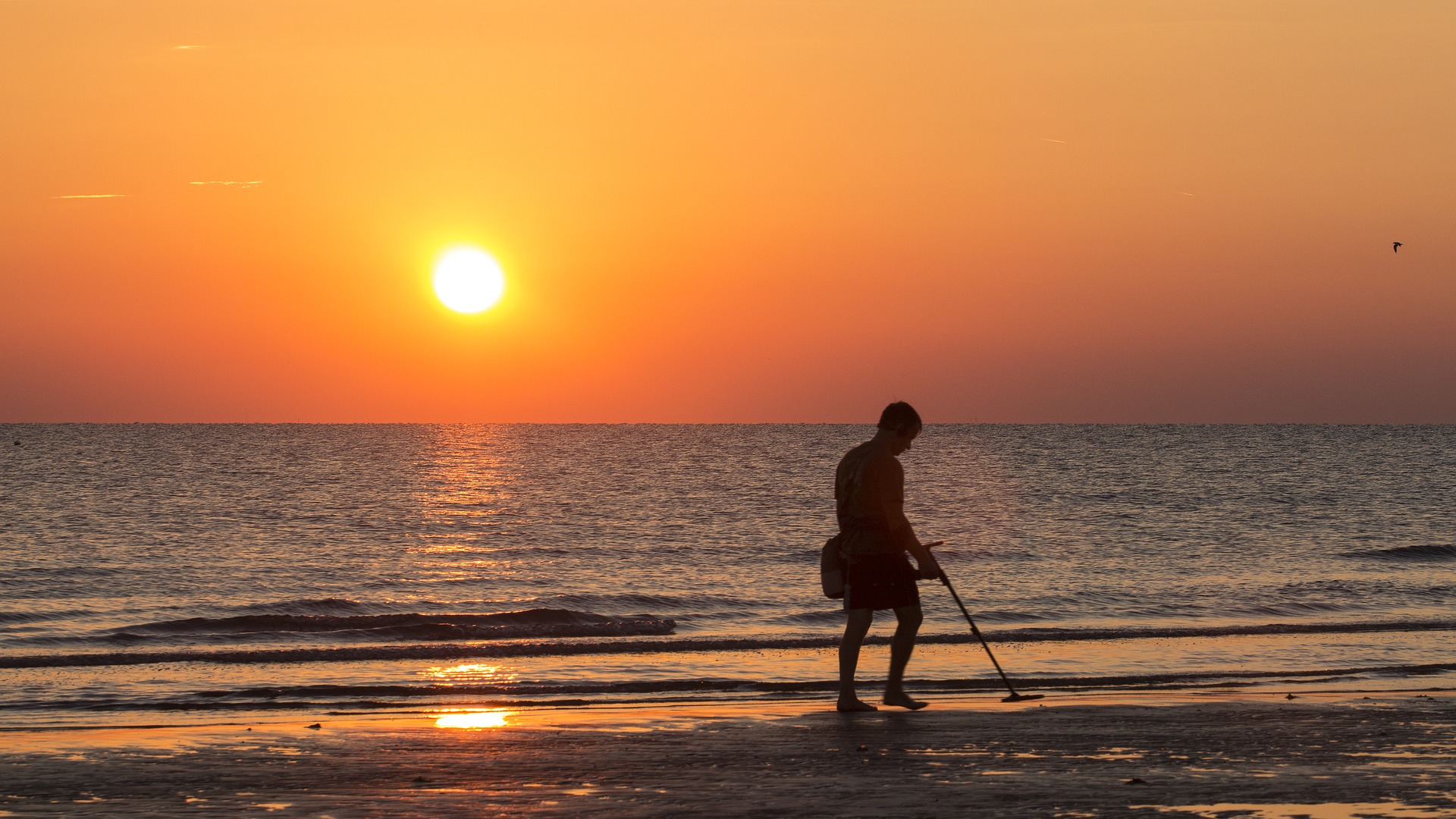 Iemand met metaaldetector op het strand