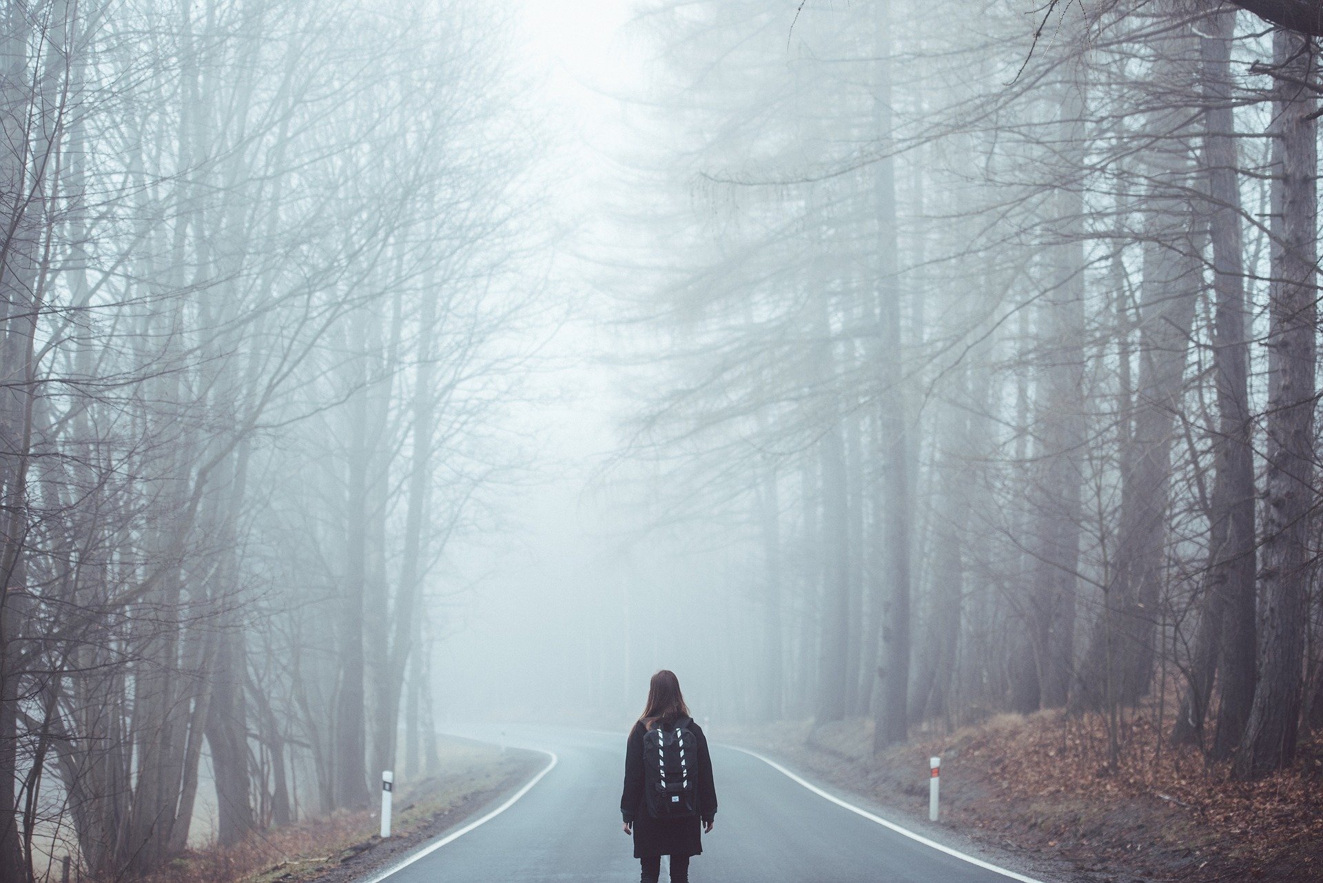 Meisje met rugzak op weg in de mist